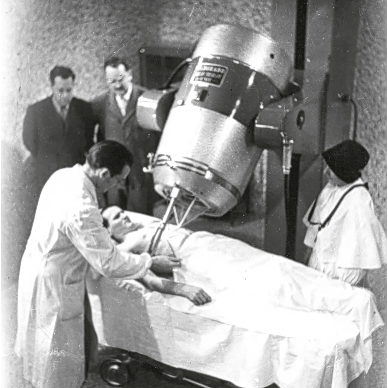 A 1950s cobalt teletherapy machine with shielded radiation head and treatment couch.
